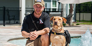 Man with a service dog next to a pool
