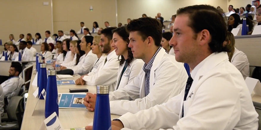 AUC Med students in a classroom wearing white coats