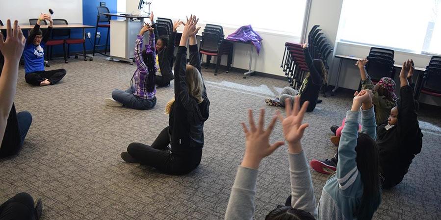 Girls in the Game participants doing yoga in a classroom