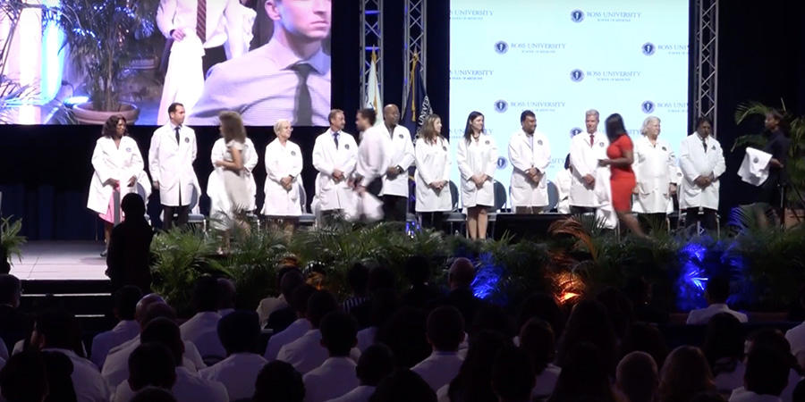 RUSM students in white coats on stage
