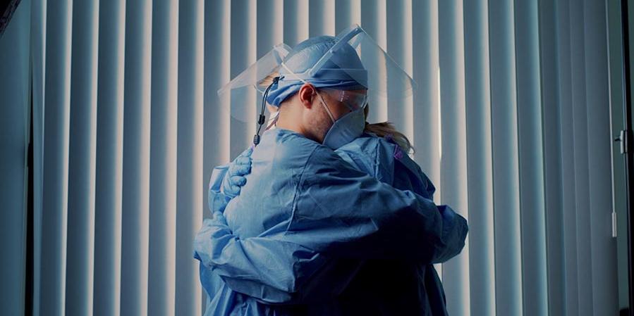 Two healthcare workers wearing PPE and hugging