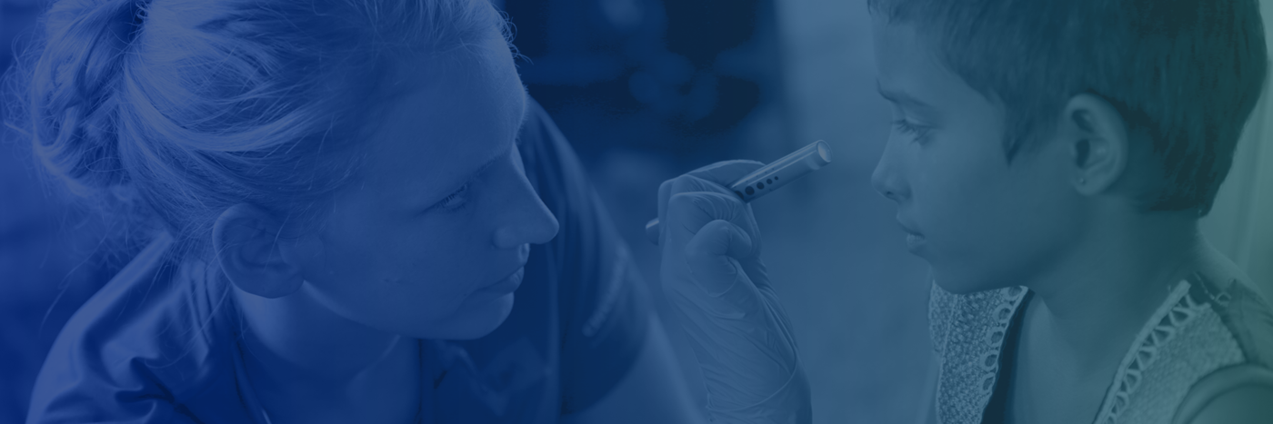 Nurse examining child's eyes with flashlight