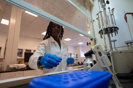 Researcher in white coat grabbing vials from centrifugal machine