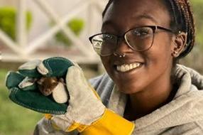 Daziah Samuels holding a small animal in her gloved hands