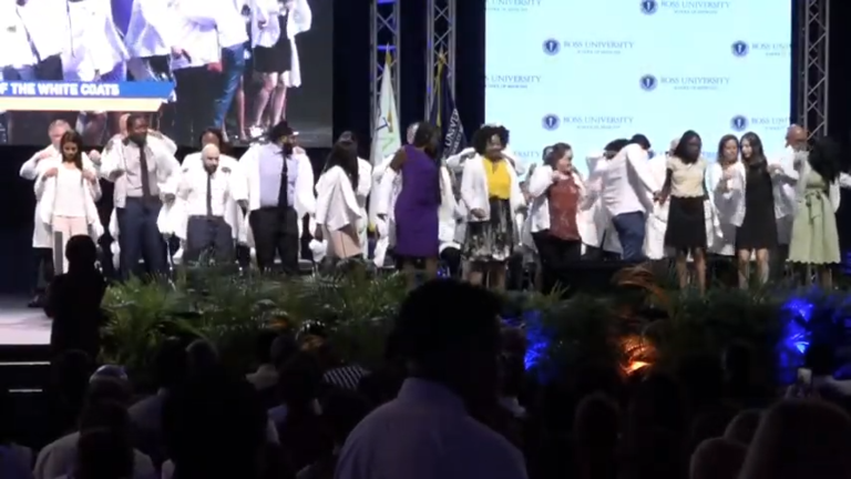 students on stage wearing white coats