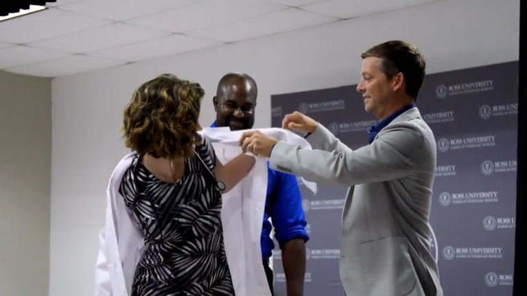 teacher helping student put on white coat