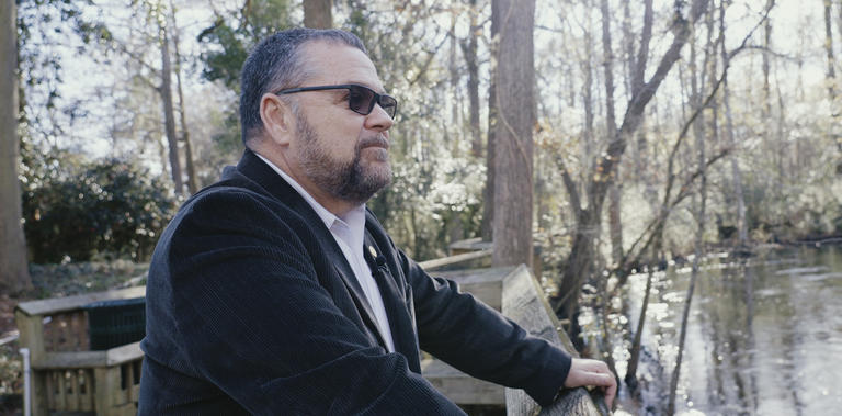 Dr Kinsey standing on a dock, looking out over water