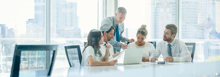 team discussing something in front of a laptop in a conference room