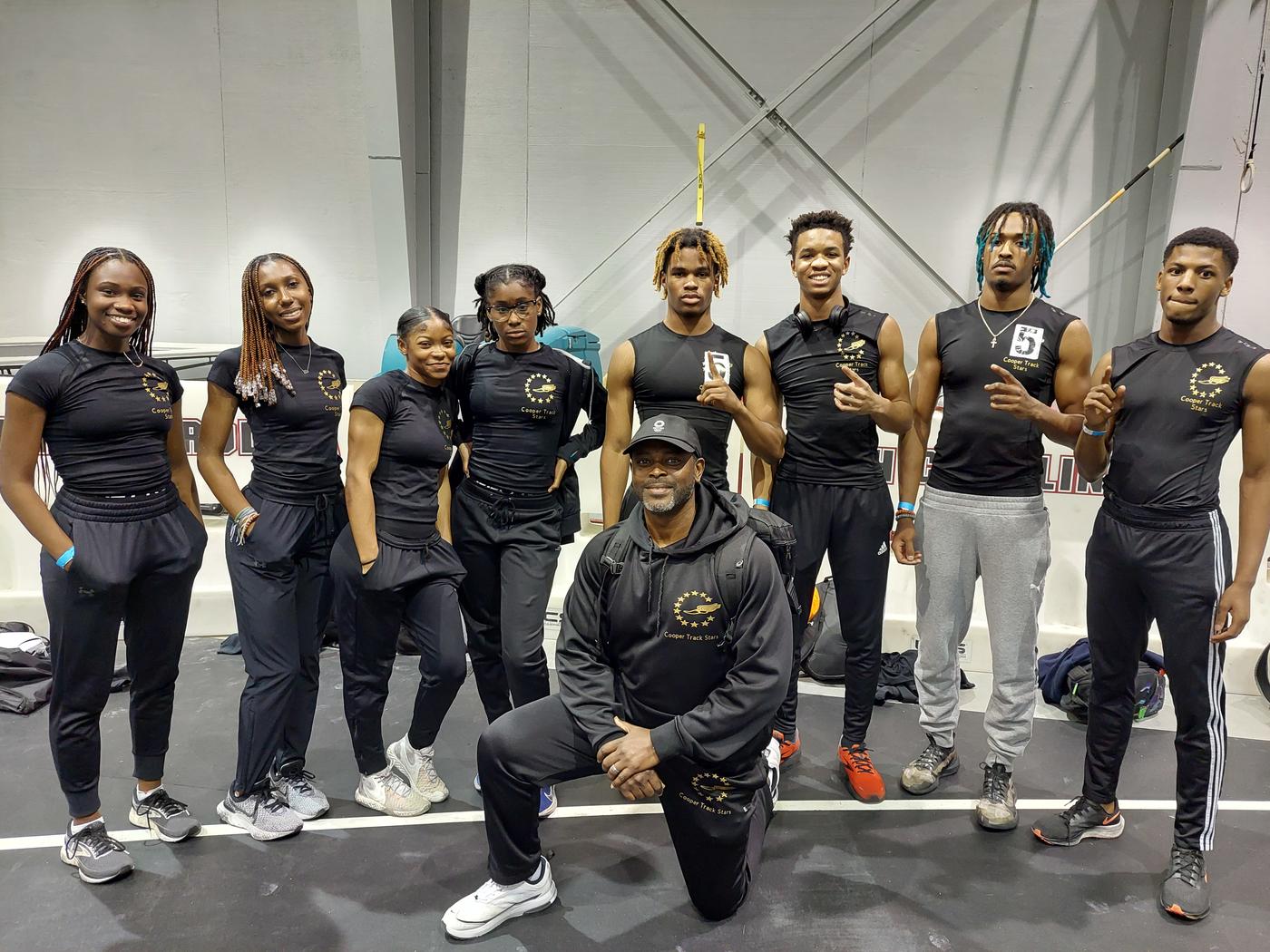 Sayon Cooper kneeling in front of his youth track team