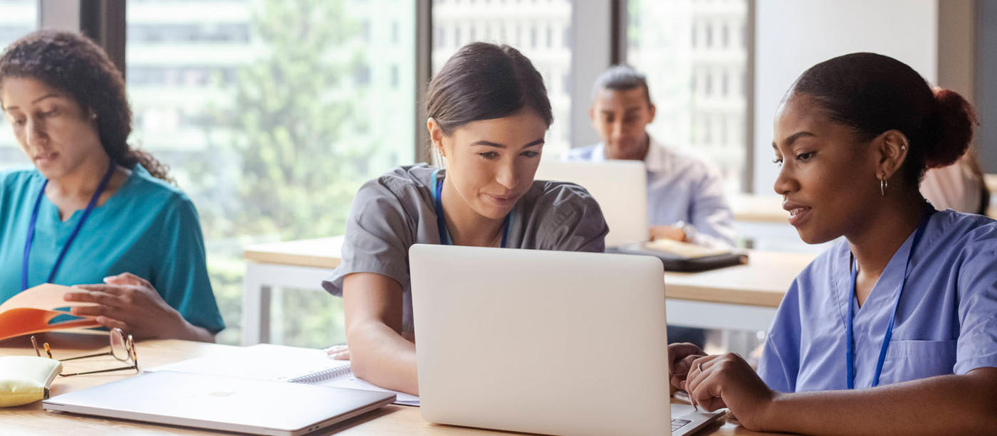 Medical students in scrubs working on laptop