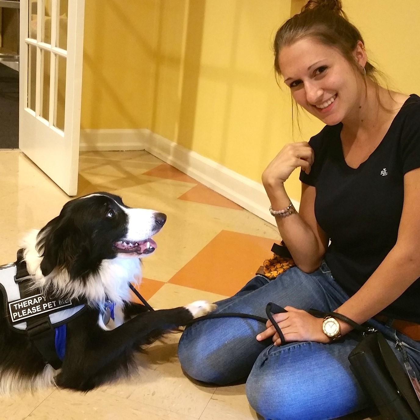 Woman sitting on floor with black and white dog.