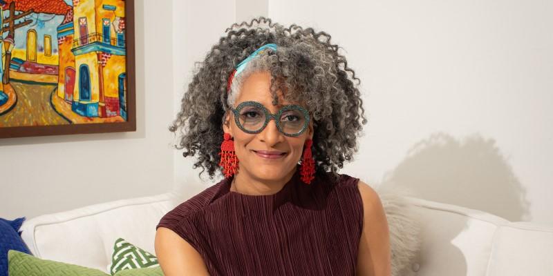 Chef, author, and TV personality Carla Hall, woman with glasses sitting on couch.