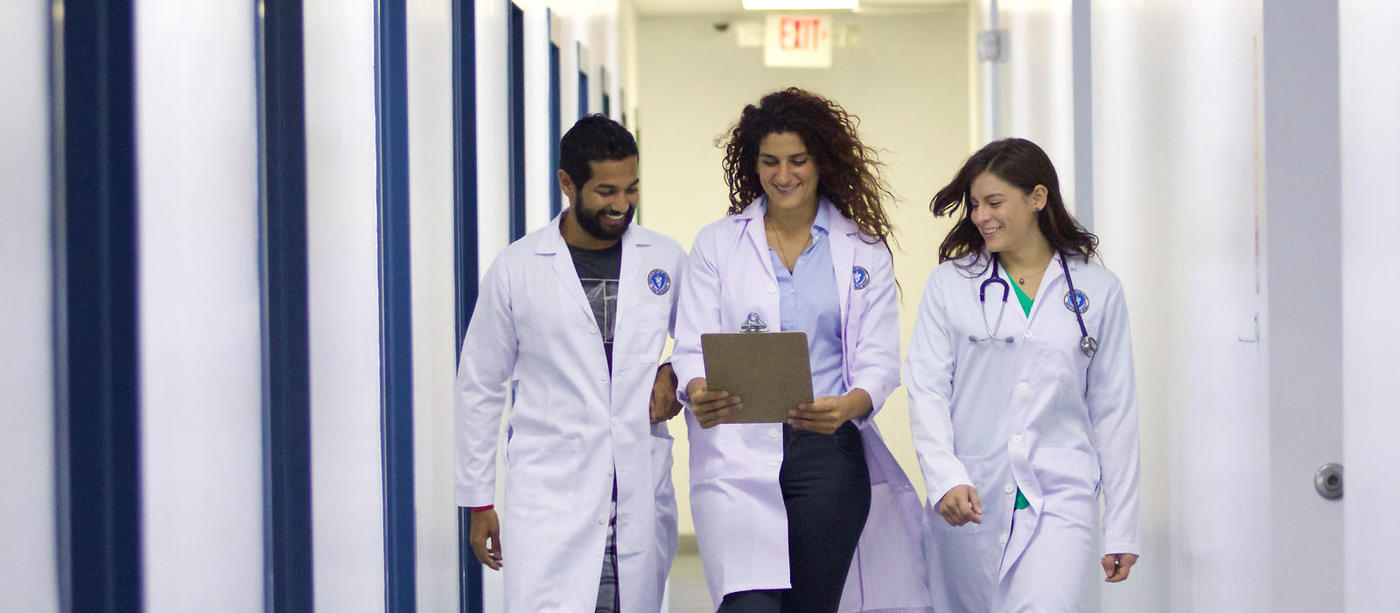 Three people walking down a hallway in lab coats