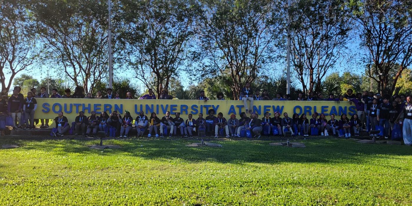 a group of students gathered around a sign that says Southern University New Orleans 