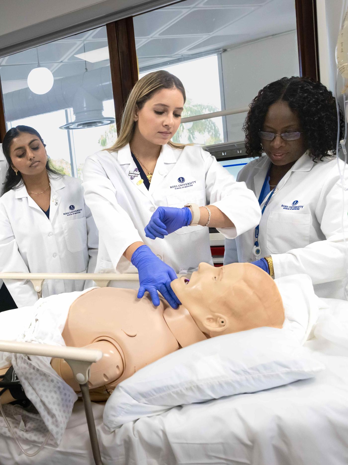 Three medical personnel working on simulation mannequin