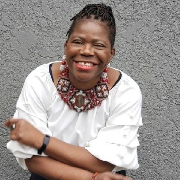 Woman, Abi Adeleke, in white shirt and ornate necklace