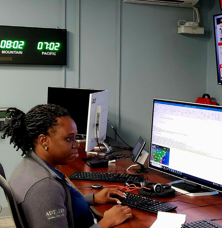 Woman at desk in front of screens of weather reports