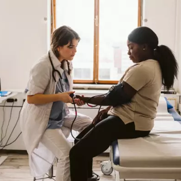 Doctor taking blood presser of woman patient in exam room.