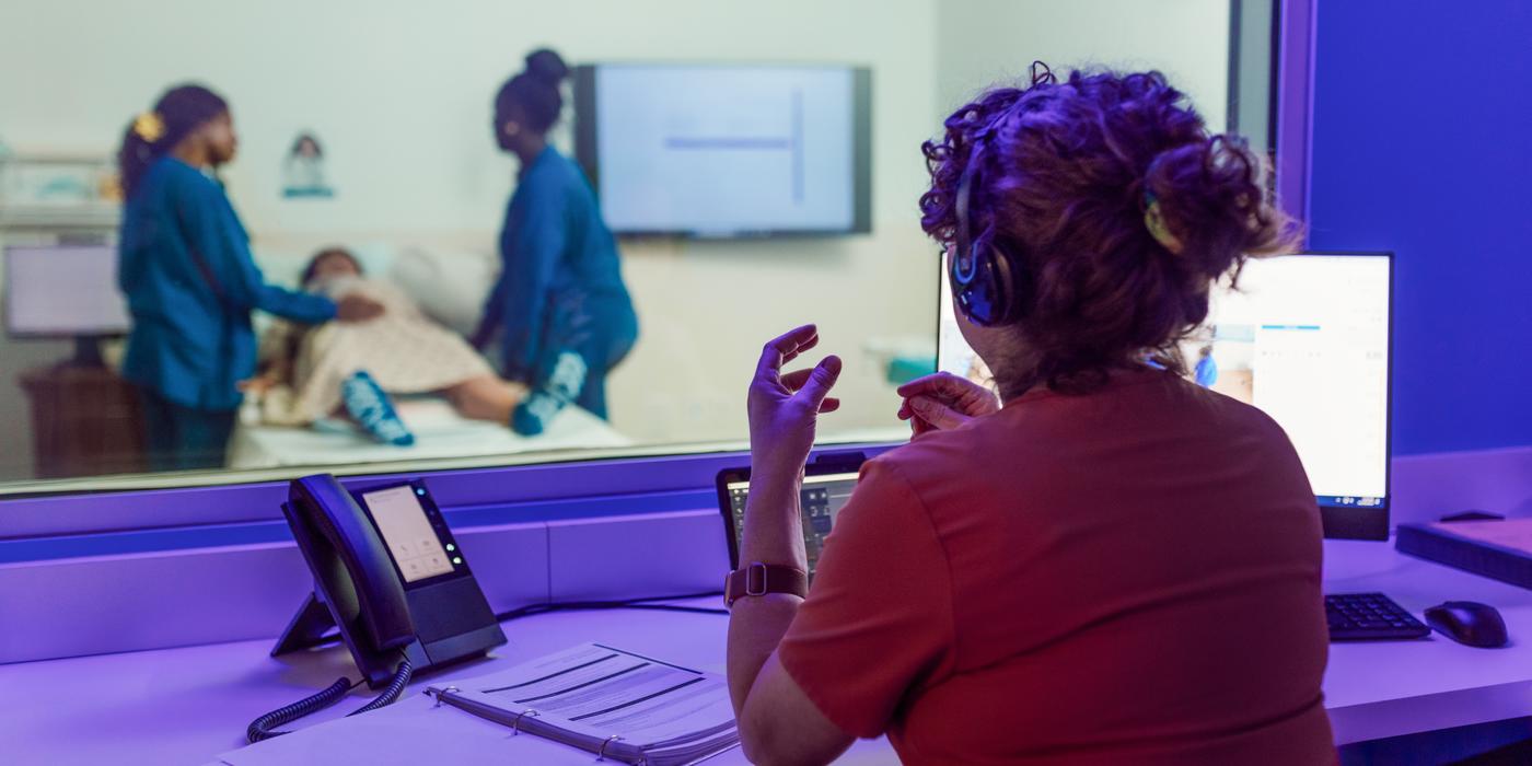 Professor Kilburg observing two students from the birth simulation's control room