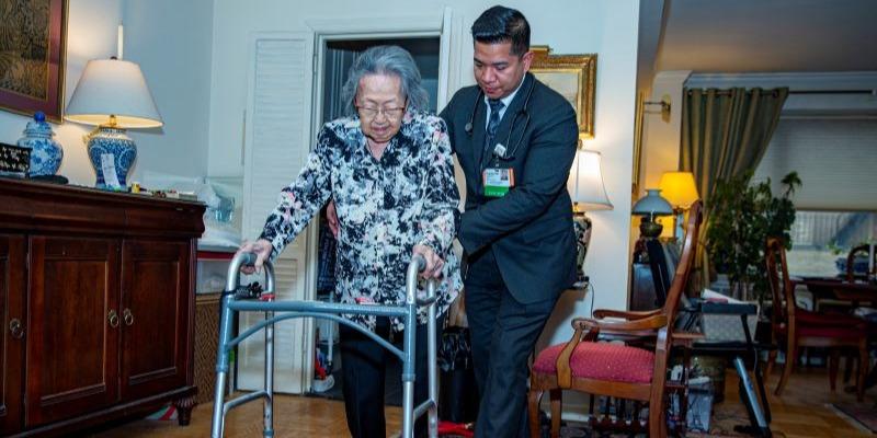 Woman with walker being assisted by man in suit.