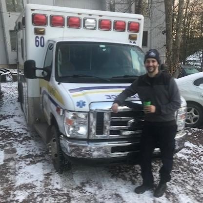 Man with beard standing in front of ambulance in snow.