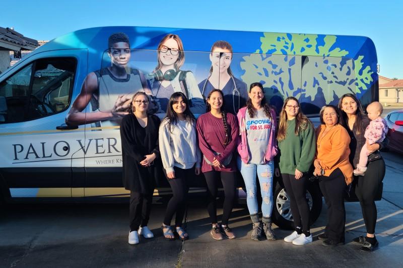 Group of women standing in front of a van.
