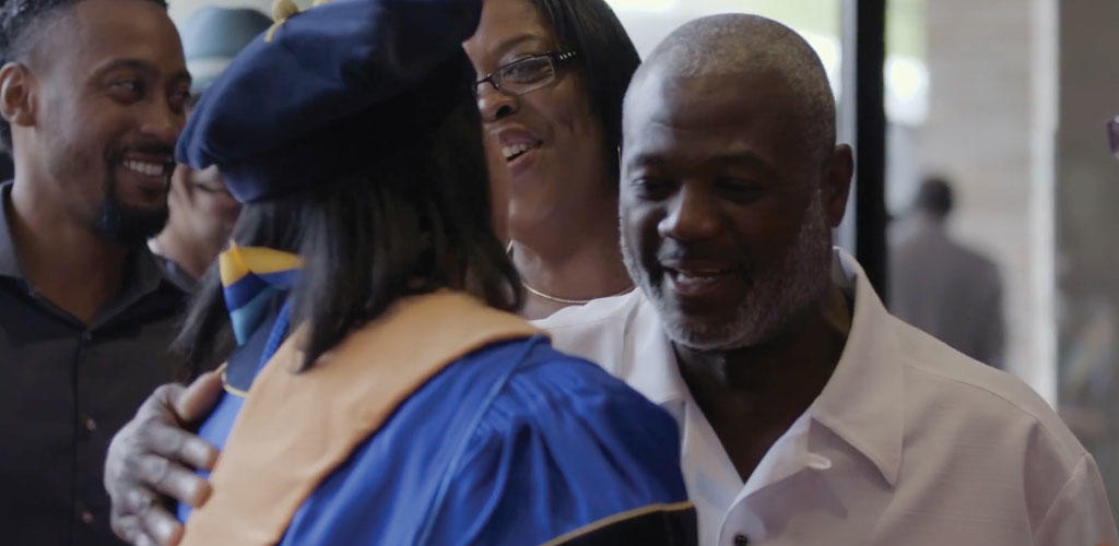 video still of graduate hugging family