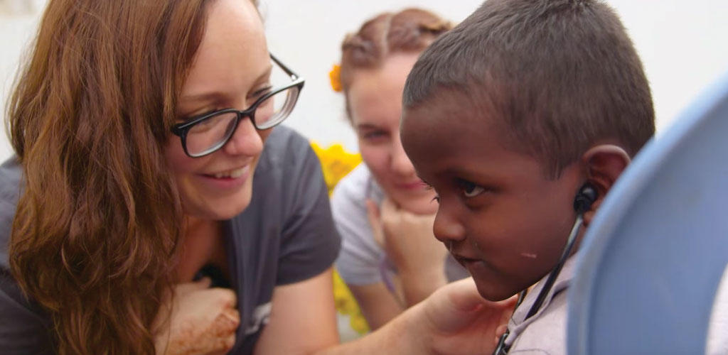 nurse in India showing a child how to use a stethoscope