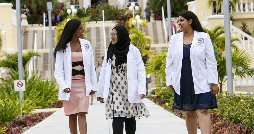 AUC students in white coats walking outside