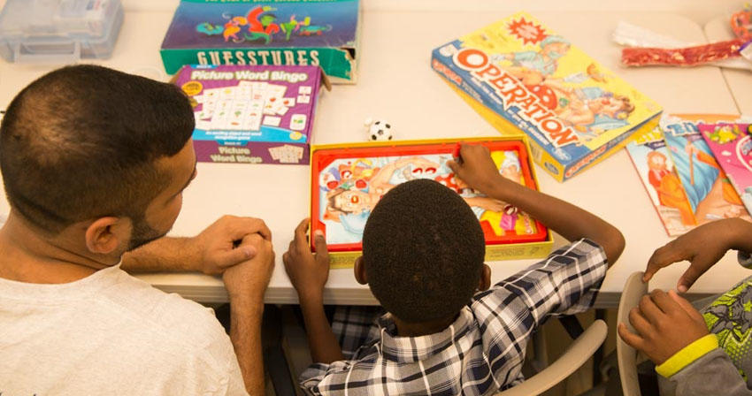 teacher playing a board game with a young student
