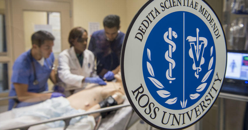 close-up of Ross U window decal with students working in a sim lab in the background