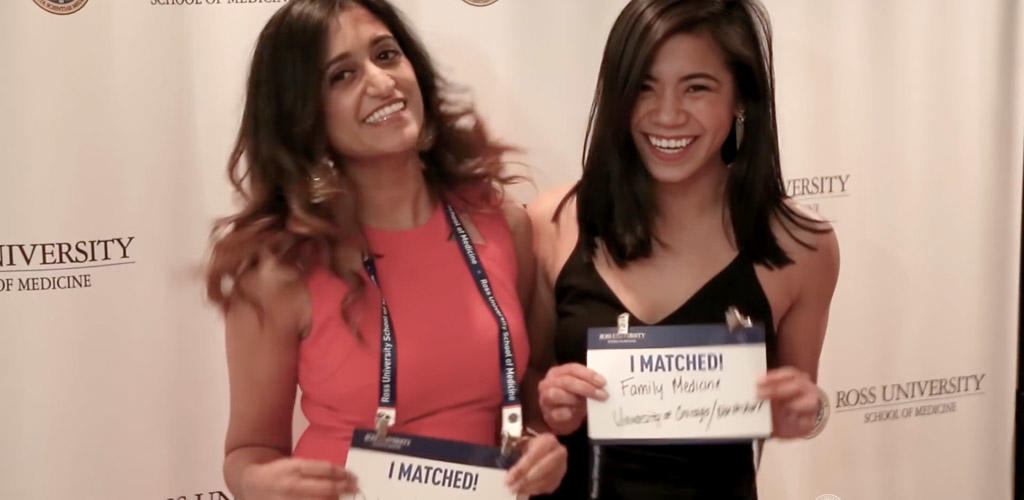 women posed in front of a backdrop holding "I Matched!" signs